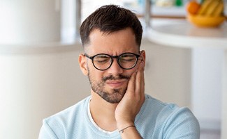 Man with black glasses experiencing toothache