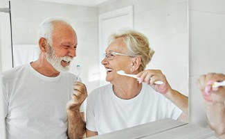 Senior couple smiling while brushing their teeth