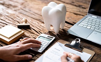 Patient calculating cost on desk with laptop