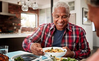 Senior man filling plate at table