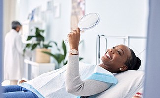 Woman smiling at reflection in handheld mirror