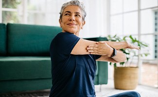 Senior woman smiling while stretching at home