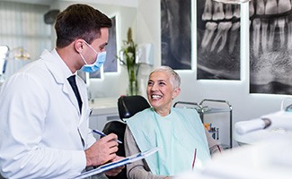 Dentist with clipboard talking to smiling patient
