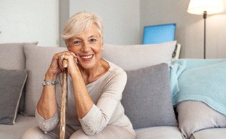 Senior woman smiling while resting her head on her cane