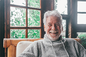 Senior man in gray sweater grinning