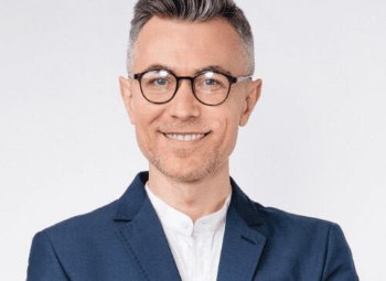 Smiling man with glasses and navy blue suit jacket