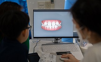 Dentist and patient looking at scan of teeth on screen