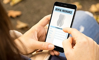Patient looking at dental insurance information on phone outside