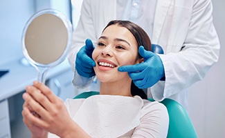 Patient smiling at reflection in handheld mirror