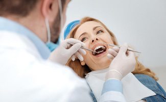 Patient smiling at dentist while they examine their teeth