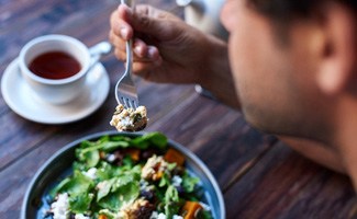 Man eating nutritious salad and drinking tea