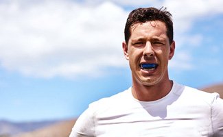 Man wearing blue mouthguard while working out outside