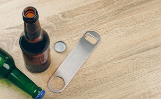 Bottle opener lying on table next to bottles