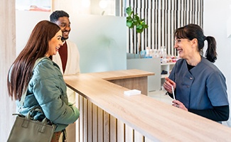 a dental team front desk member and patient 