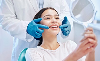 Patient smiling at reflection in handheld mirror